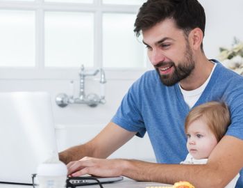 padre-che-lavora-al-computer-portatile-mentre-si-tiene-bambino-1600x800