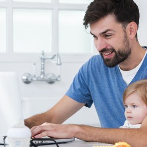 padre-che-lavora-al-computer-portatile-mentre-si-tiene-bambino-1600x800